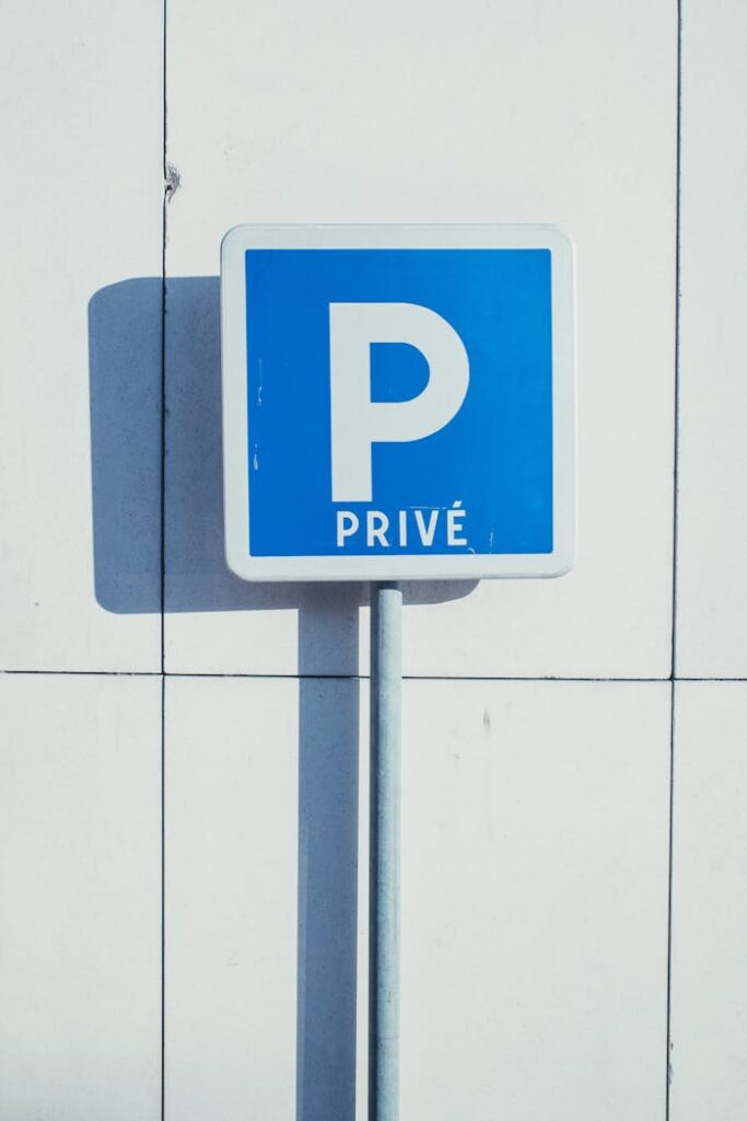 Blue 'P Privé' parking sign on a wall in Compiègne, France, sunny day.
